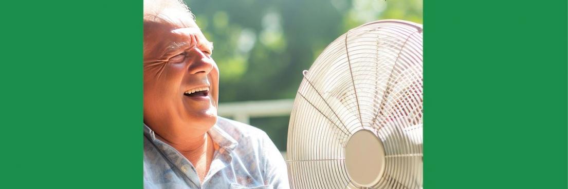 Mann mit hellblauem Hemd sitzt neben einem großen Ventilator im Freien. Text: 'Medizin im Zeichen des Klimawandels'.
